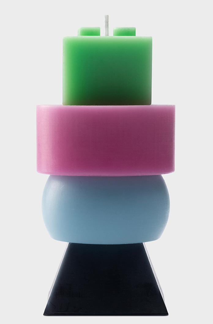 Colorful stacked candles in geometric shapes featuring green pink blue and black segments. Modern design adds artistic flair to home decor and relaxation ambiance.